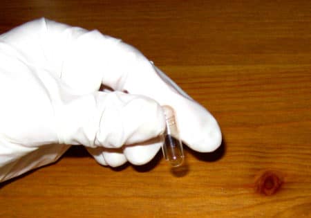 S gloved hand holding a single capsule