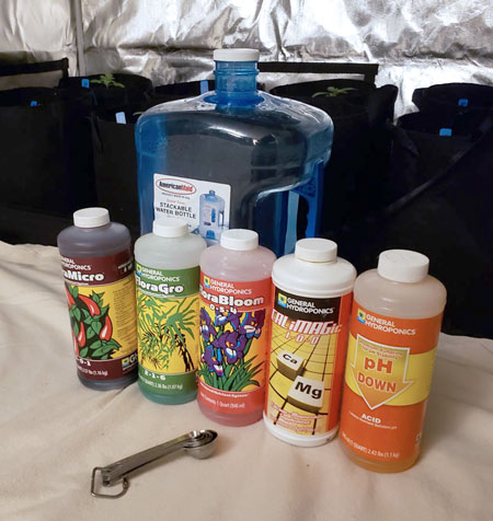 General Hydroponics Nutrients Flora Trio line plus CaliMagic and PH Down. Mixing cannabis nutrients on the floor.